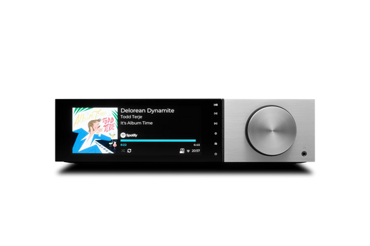 Der Cambridge Audio EVO 150 Delorean Edition All-in-One Player in Silber verfügt über einen großen silbernen Lautstärkeregler und zeigt den Song "Delorean Dynamite" von Todd Terje aus "It's Album Time" an, der gerade auf Spotify läuft.