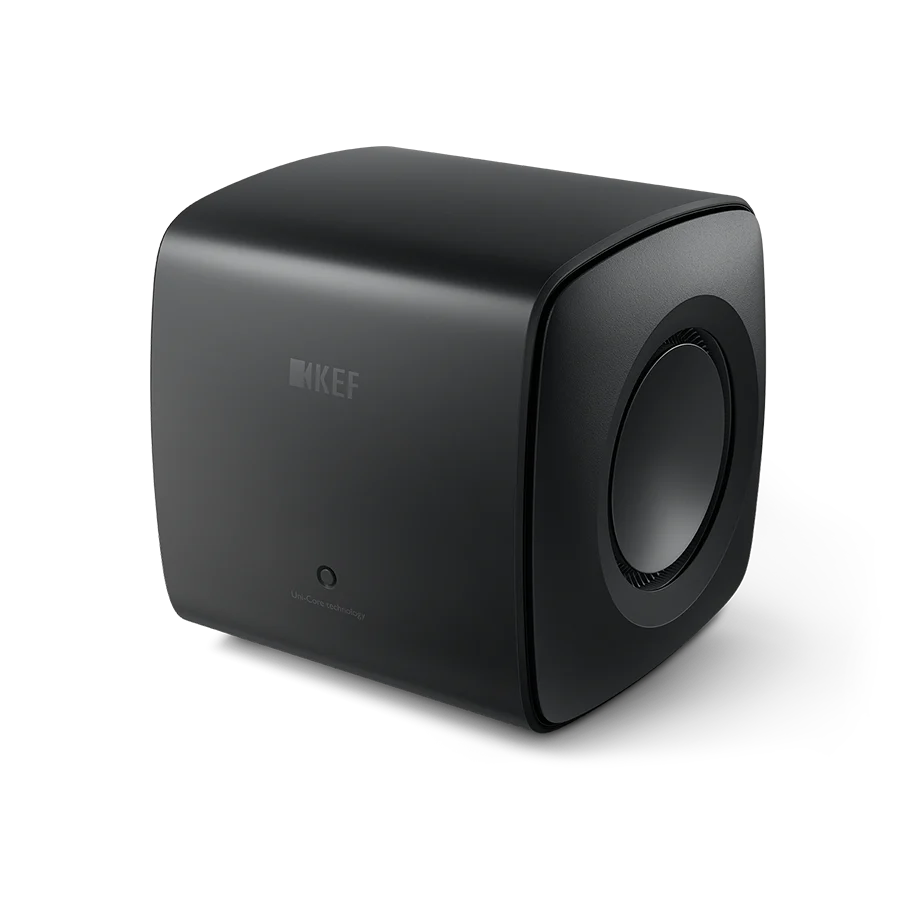 Der KEF KC62 Subwoofer in Carbon Black ist ein kompakter, würfelförmiger Lautsprecher mit abgerundeten Kanten, dezentem Branding auf der Vorderseite, einer sichtbaren seitlichen Lautsprechermembran und einem hochmodernen Design mit innovativer Uni-Core®-Technologie.