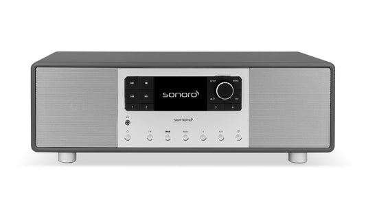 Das Sonoro Primus in Graphit (matt) - Silber ist ein modernes, rechteckiges Tischradio mit digitalem Display, zentralem Bedienknopf und zwei Lautsprechergittern, das ein unvergleichliches Hörerlebnis und einen beeindruckenden 360°-Klang bietet.