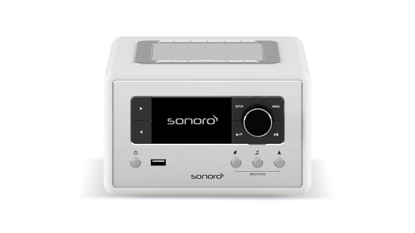 Der Sonoro Relax in Weiß (hochglänzend) - Silber verfügt über ein digitales Display, Bedientasten, einen großen Drehknopf, USB-Anschluss und ein oberes Lautsprechergitter - ideal für Wellness-Momente oder Meditationsübungen zu Hause.