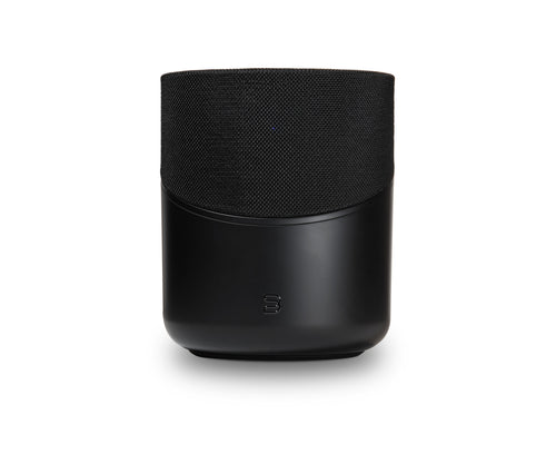 Der Bluesound PULSE M in Schwarz hat eine stoffbespannte Oberseite, eine glatte Unterseite und ein kleines Frontlogo. Dieser kabellose Lautsprecher bietet HiFi-Stereoklang und 360° Klangverteilung. Abgebildet vor einem weißen Hintergrund.