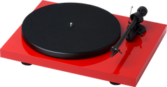 Ein roter Pro-Ject Debut Recordmaster II Plattenspieler mit schwarzem Plattenteller und Tonarm, gesehen aus einem leicht erhöhten Winkel vor einem weißen Hintergrund.