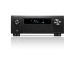 Frontansicht des Denon AVC-X6800H AV-Receivers in Schwarz mit großen Lautstärke- und Eingangsknöpfen, Display mit Blu-ray Dolby Atmos, HEOS® Built-in Logo sowie diversen Bedientasten. Das Gerät spiegelt sich auf einer glänzenden Oberfläche.