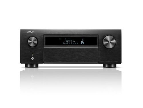 Frontansicht des Denon AVC-X6800H AV-Receivers in Schwarz mit großen Lautstärke- und Eingangsknöpfen, Display mit Blu-ray Dolby Atmos, HEOS® Built-in Logo sowie diversen Bedientasten. Das Gerät spiegelt sich auf einer glänzenden Oberfläche.