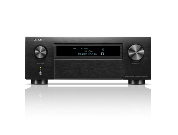 Frontansicht des Denon AVC-X6800H AV-Receivers in Schwarz mit großen Lautstärke- und Eingangsknöpfen, Display mit Blu-ray Dolby Atmos, HEOS® Built-in Logo sowie diversen Bedientasten. Das Gerät spiegelt sich auf einer glänzenden Oberfläche.