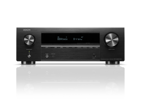 Ein Denon AVR-X1800H DAB AV-Receiver in Schwarz mit HEOS® Built-in, Frontdisplay mit Dolby Atmos und B-ray, großen Lautstärke-/Wahlschaltern, Steuertasten und Eingangsanschlüssen auf einer reflektierenden Oberfläche.