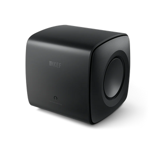 Der KEF KC62 Subwoofer in Carbon Black ist ein kompakter, würfelförmiger Lautsprecher mit abgerundeten Kanten, dezentem Branding auf der Vorderseite, einer sichtbaren seitlichen Lautsprechermembran und einem hochmodernen Design mit innovativer Uni-Core®-Technologie.