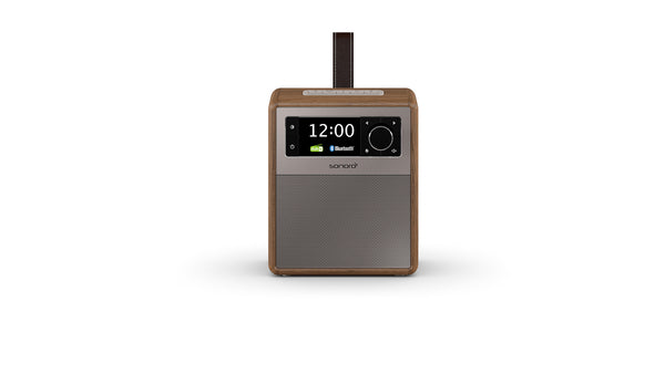 Das Sonoro Easy in Walnuss-Silber ist ein kompaktes, rechteckiges Digitalradio mit Holzrahmen, grauer Frontplatte, digitaler 12-Uhr-Anzeige, Bluetooth und Bedientasten sowie einem braunen Tragegriff oben für praktische Mobilität.
