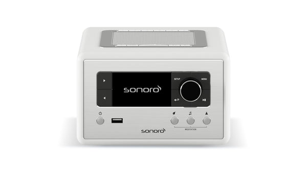 Der Sonoro Relax in Weiß (hochglänzend) - Silber verfügt über ein digitales Display, Bedientasten, einen großen Drehknopf, USB-Anschluss und ein oberes Lautsprechergitter - ideal für Wellness-Momente oder Meditationsübungen zu Hause.